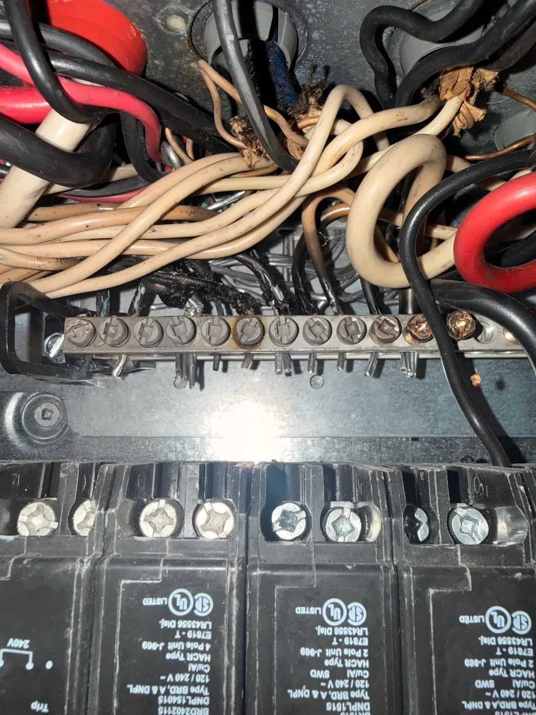 Scorched neutral bus bar with oxidized aluminum branch wiring terminations inside an electrical panel