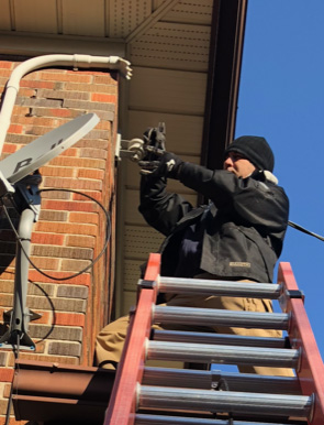 Inline Electric electrician on a ladder performing an exterior electrical service upgrade in Cambridge, Ontario