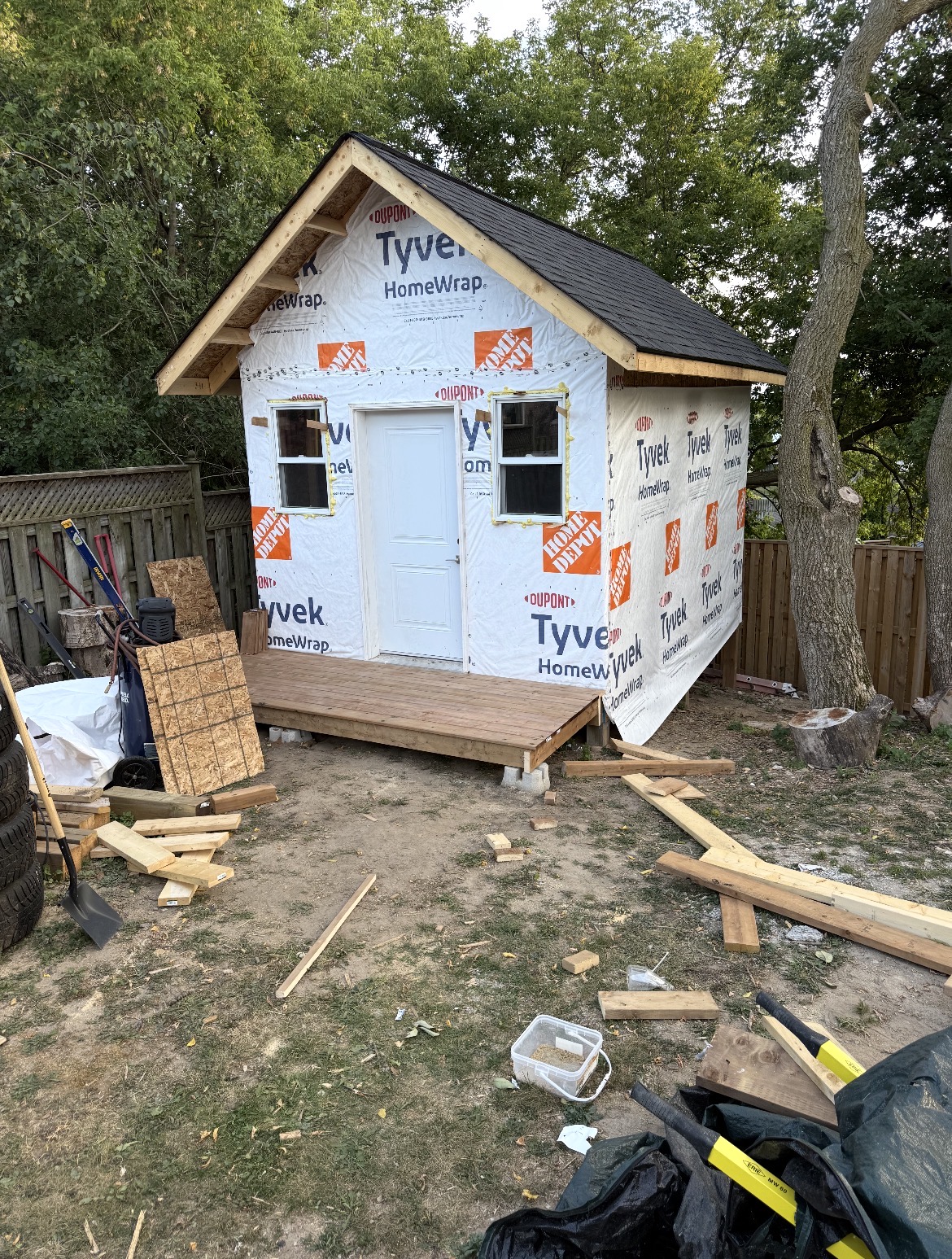 Shed build stage 4 — Tyvek house wrap, door, and windows installed